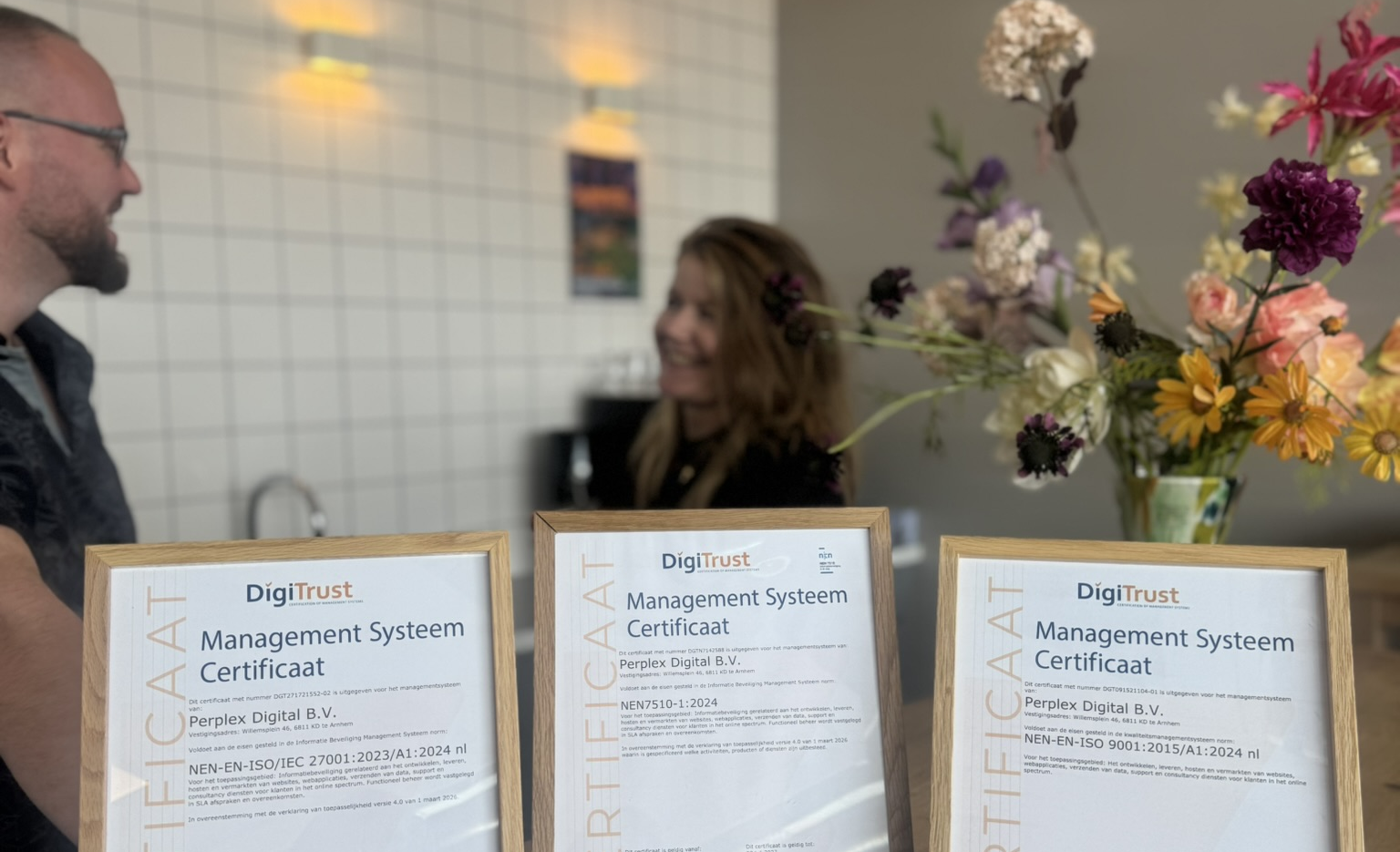 ISO- en NEN-certificaten van Perplex op tafel, met collega's in gesprek